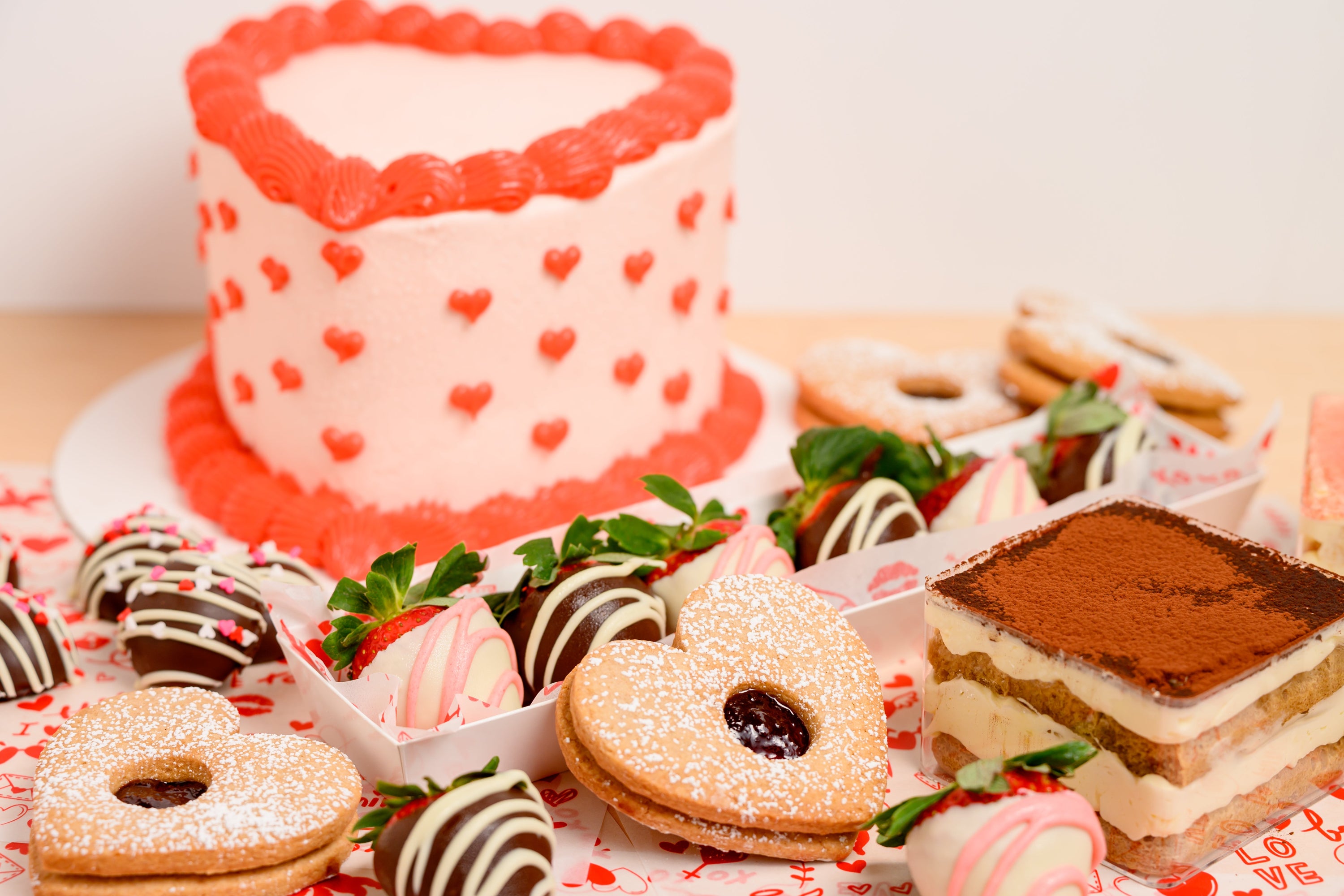Valentine's Day-themed dessert table with a heart-shaped cake and various pastries.